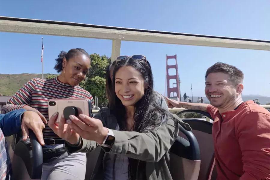 A group of visitors take a selfie on a bus tour near the Golden Gate Bridge. 贝博体彩app，加州.