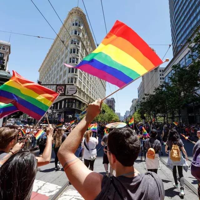 Le persone che camminano nella parata del Pride di San Francisco sventolano bandiere arcobaleno.